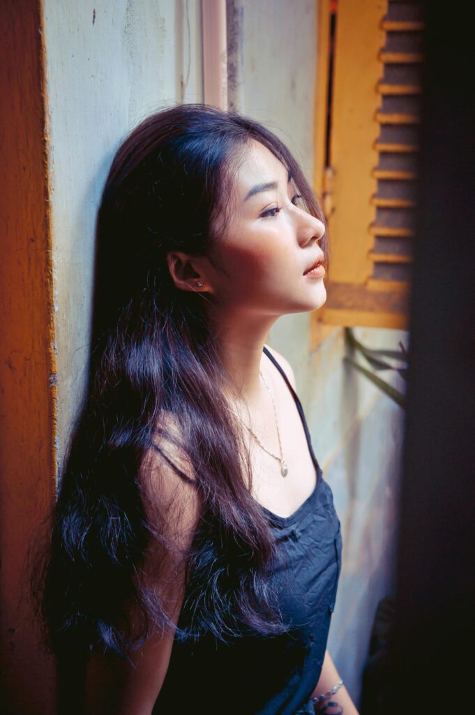 Woman in black dress leaning against wall.