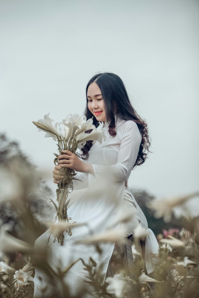 Woman in white dress holding white flowers.