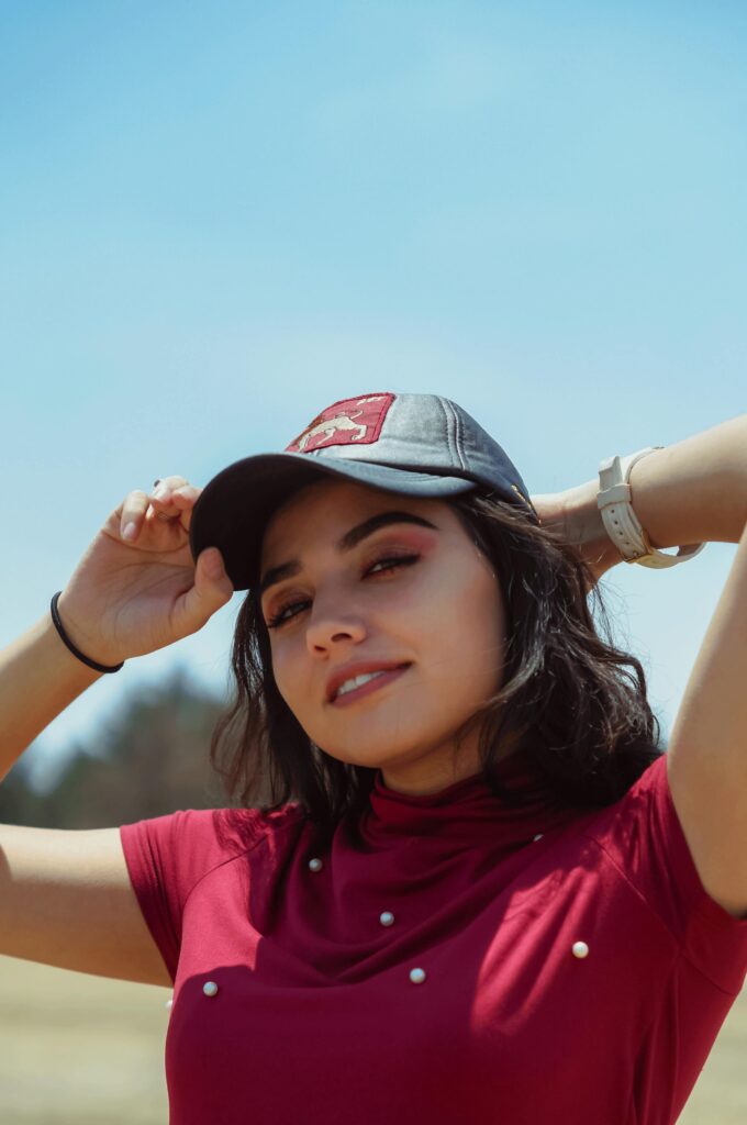 Person posing outdoors wearing a cap.