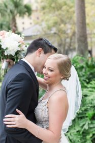 Bride and groom embracing outdoors, smiling.