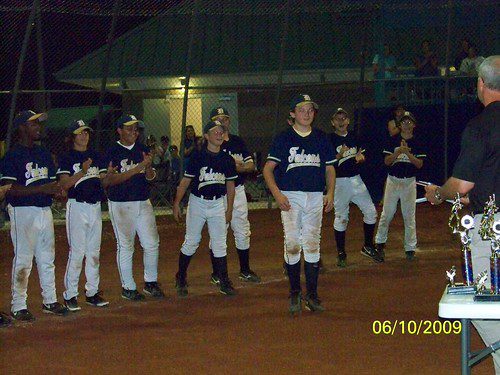 Youth baseball team receiving awards at night.