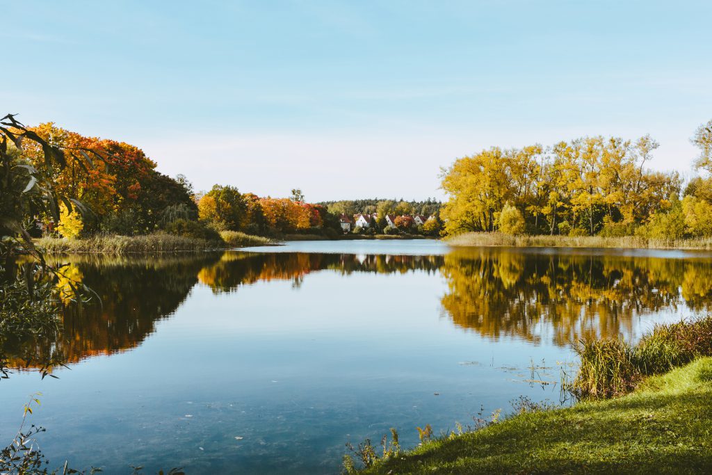 Calm lake reflecting autumn trees and sky.